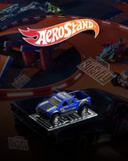 A clear acrylic stand with the name 'AeroStand' displayed on a table with Hot Wheels cars and tracks.